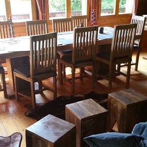 Aufenthaltsraum des Berghauses mit langer Holztafel und Holzhockern